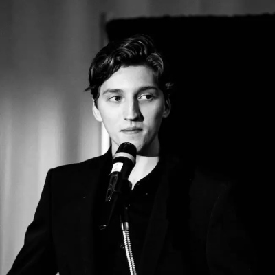 a black and white photo of a man in a suit holding a microphone