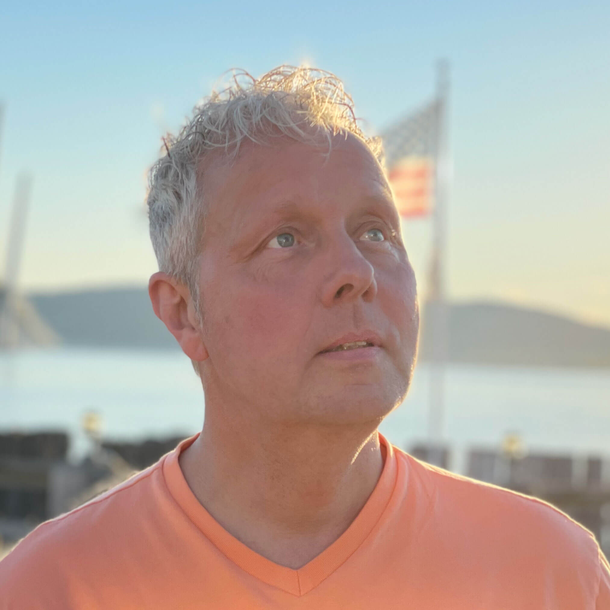 a man in an orange shirt looking off into the distance