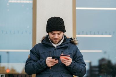 a man in a winter coat looking at his cell phone
