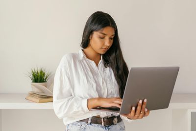 a woman in a white shirt is using a laptop