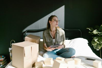 a woman sitting on a bed surrounded by boxes