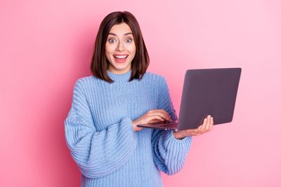 a woman in a blue sweater is holding a laptop
