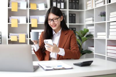 a female instagram expert sitting at a desk using a cell phone for instagram strategy to  help her client increase engagement