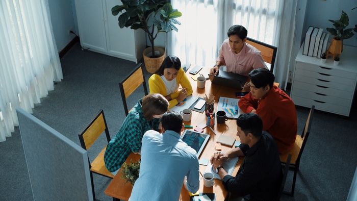 a group of people sitting around a wooden table preview image